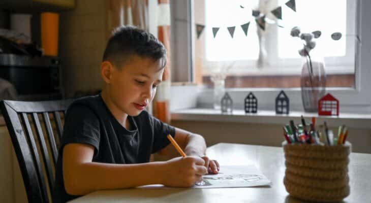 A 10-year-old boy draws a drawing with colored pencils