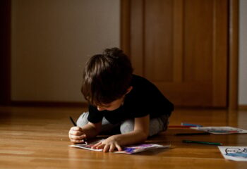 A little boy 5 years old draws a drawing with colored pencils