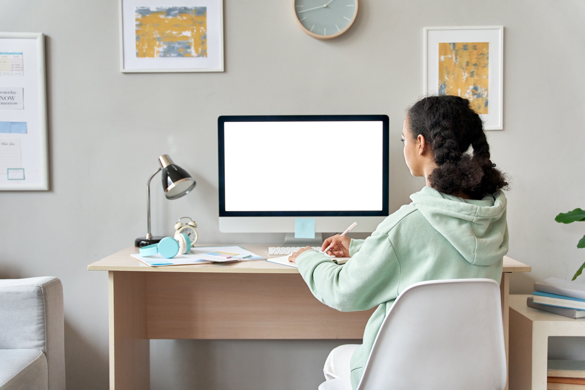 African teen school girl online learning at home looking at mockup pc screen.