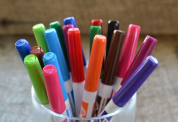 Colorful white board dry erase magic markers in a container on a desk.