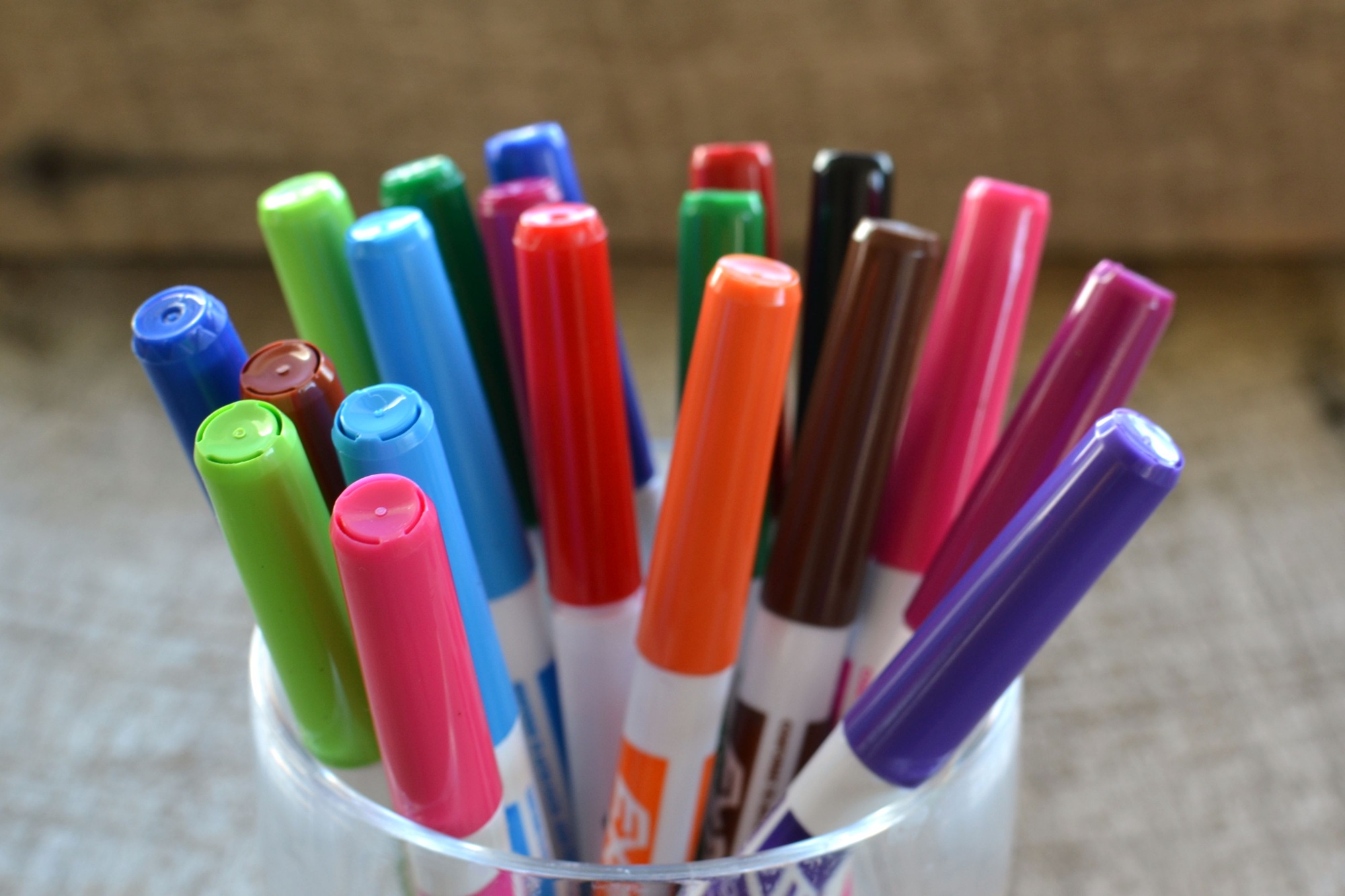 Colorful white board dry erase magic markers in a container on a desk.