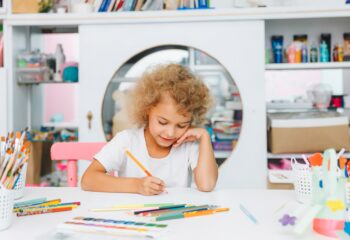 Cute little blonde preschooler girl draws at home