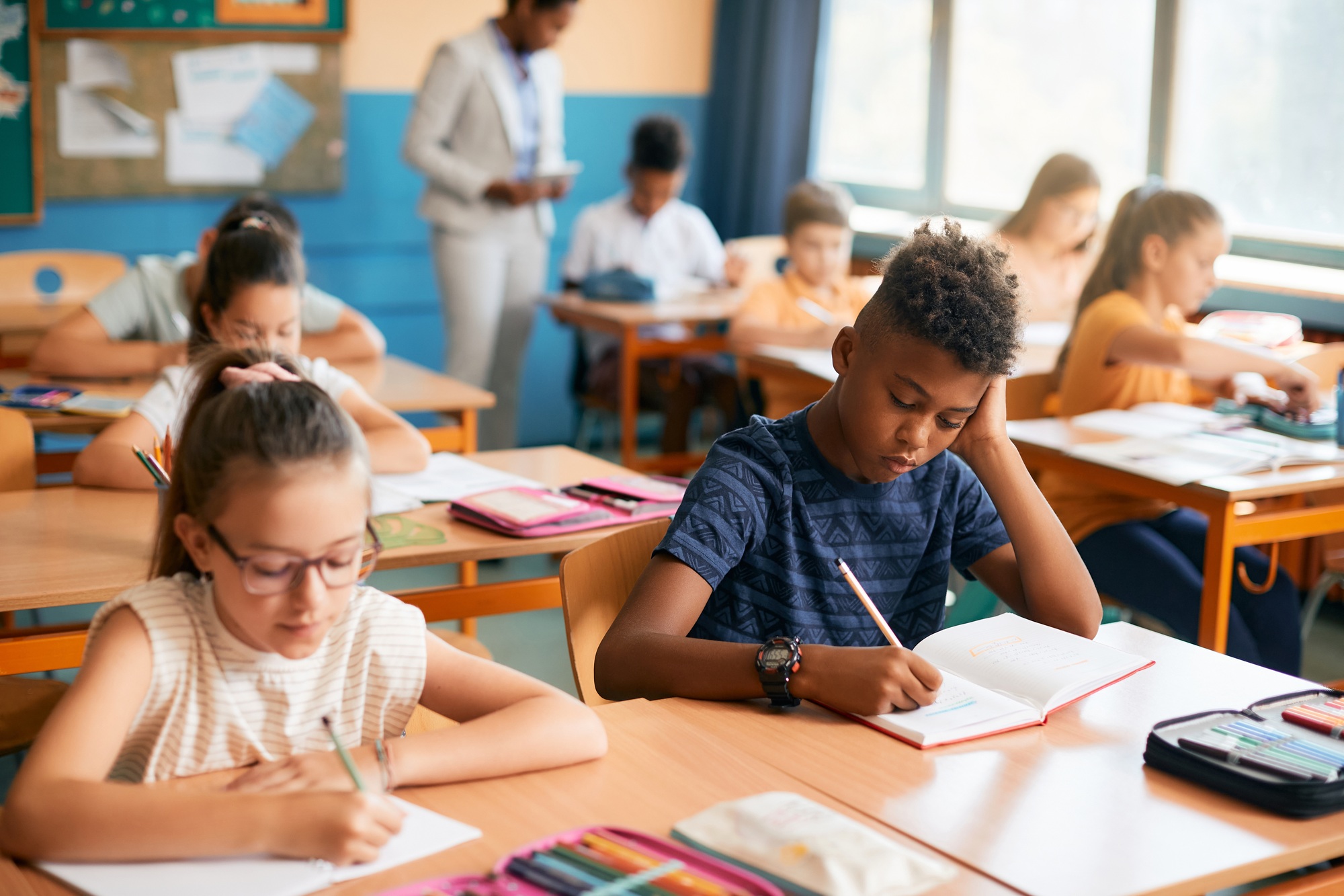 Elementary students writing dictation during a class in the classroom.