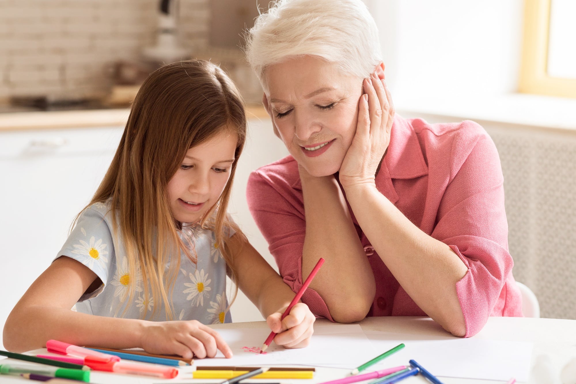 Grandparent and grandchild drawing with color pencils in kitchen