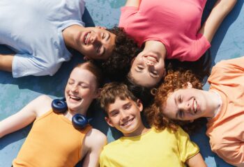 Group of happy teenagers kids outdoors on the sportive field at daytime