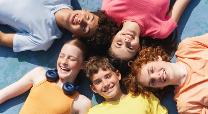 Group of happy teenagers kids outdoors on the sportive field at daytime