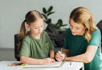 mother and daughter drawing with colored pencils at home