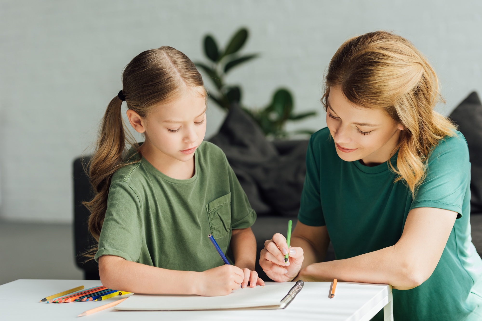 mother and daughter drawing with colored pencils at home