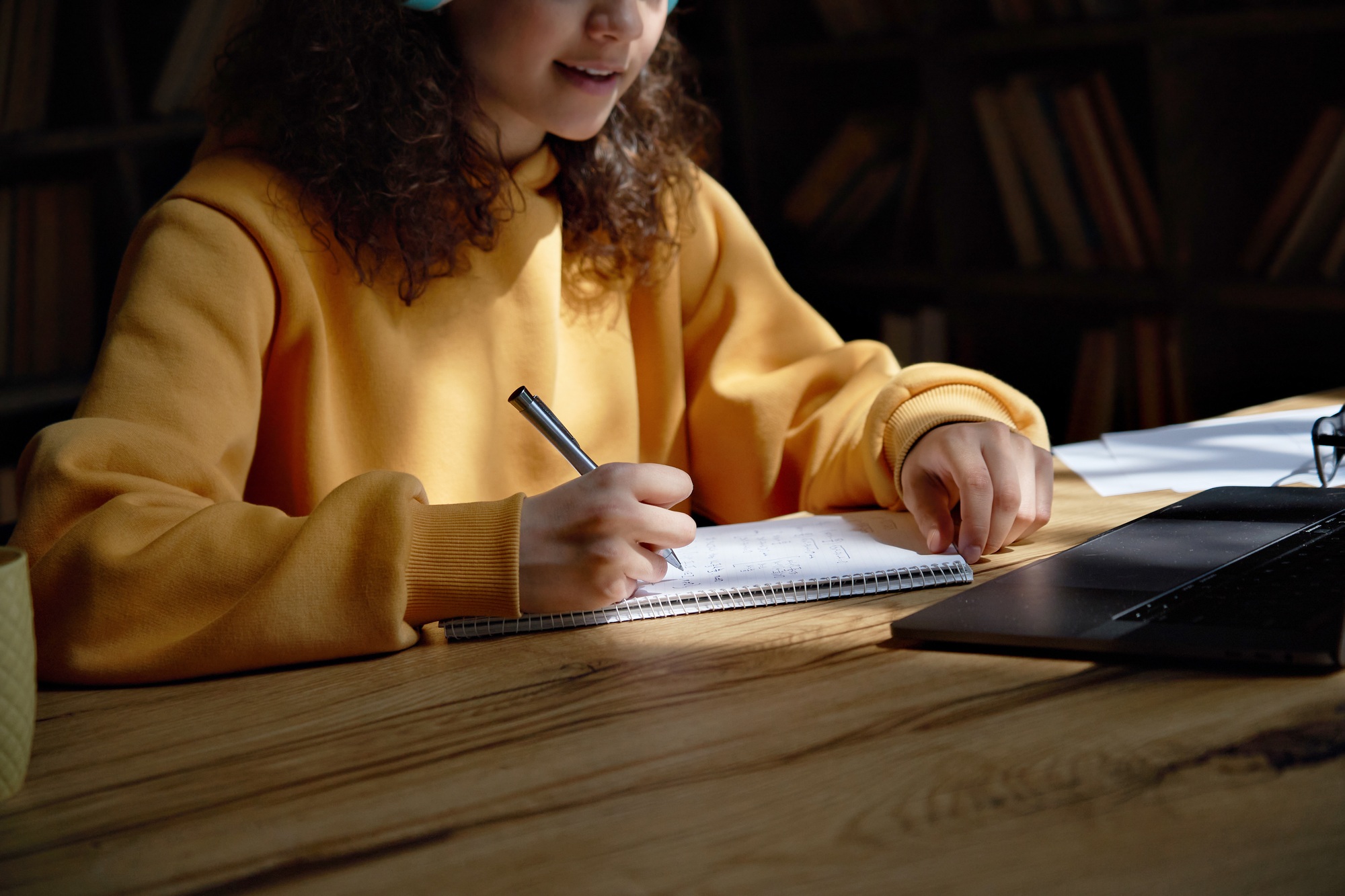 Teen girl college student studying at home making notes doing homework, closeup.