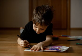 A little boy 5 years old draws a drawing with colored pencils