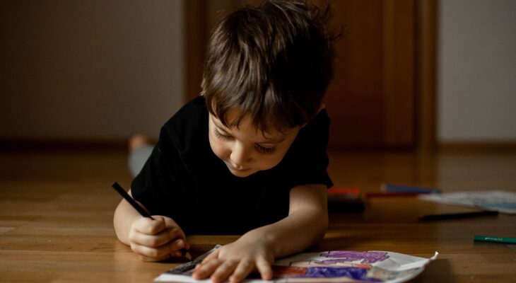 A little boy 5 years old draws a drawing with colored pencils