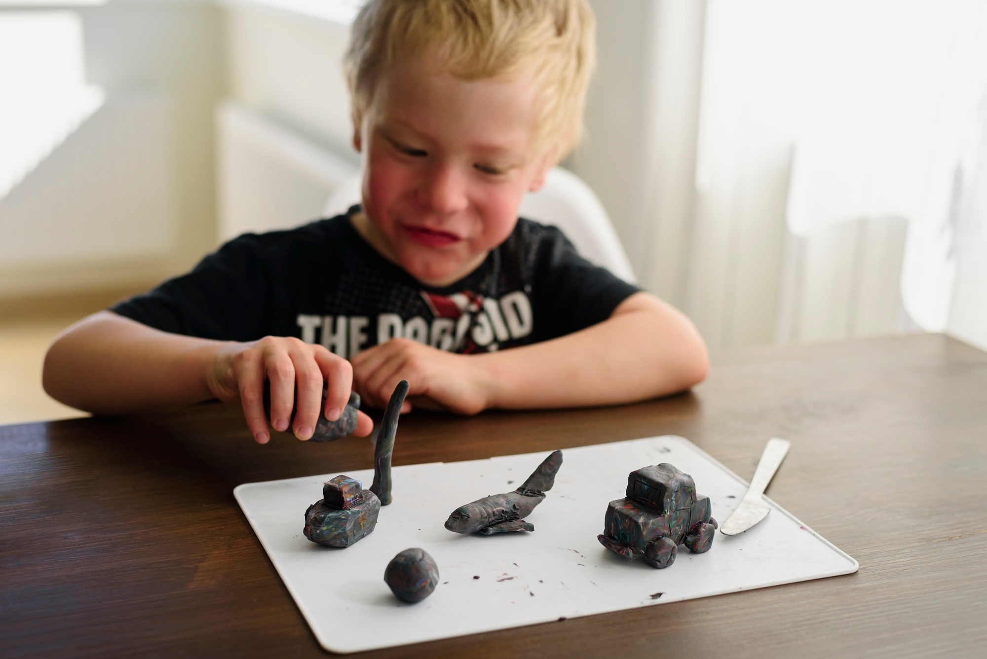 Boy sculpting toys from modelling clay and playing