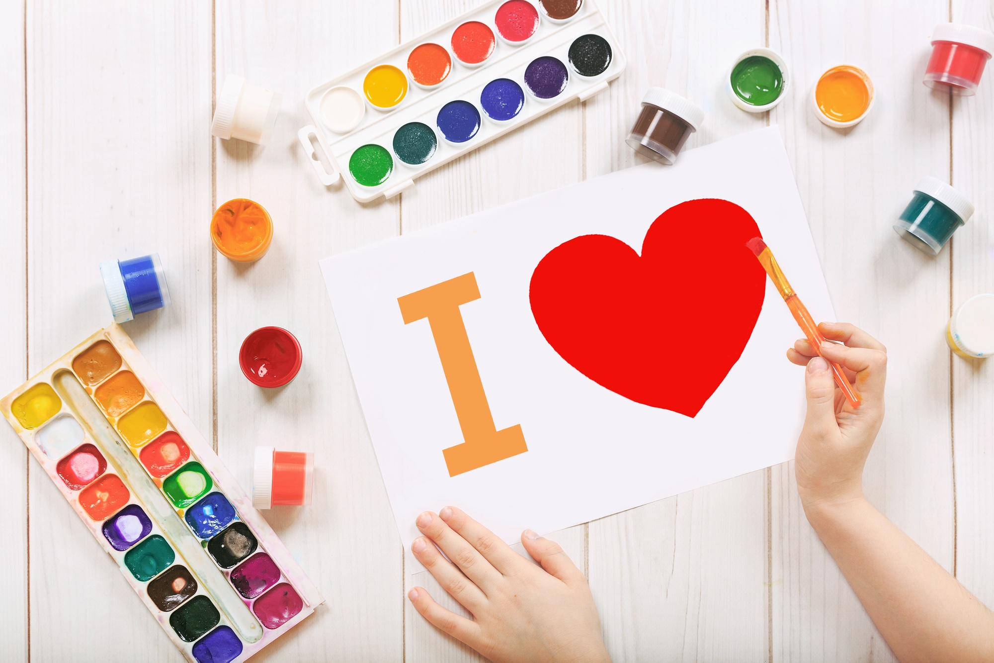 Child draw red heart on paper.