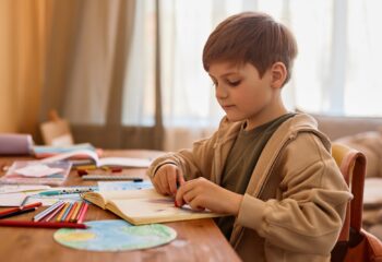 Cute boy drawing at table