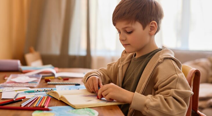 Cute boy drawing at table