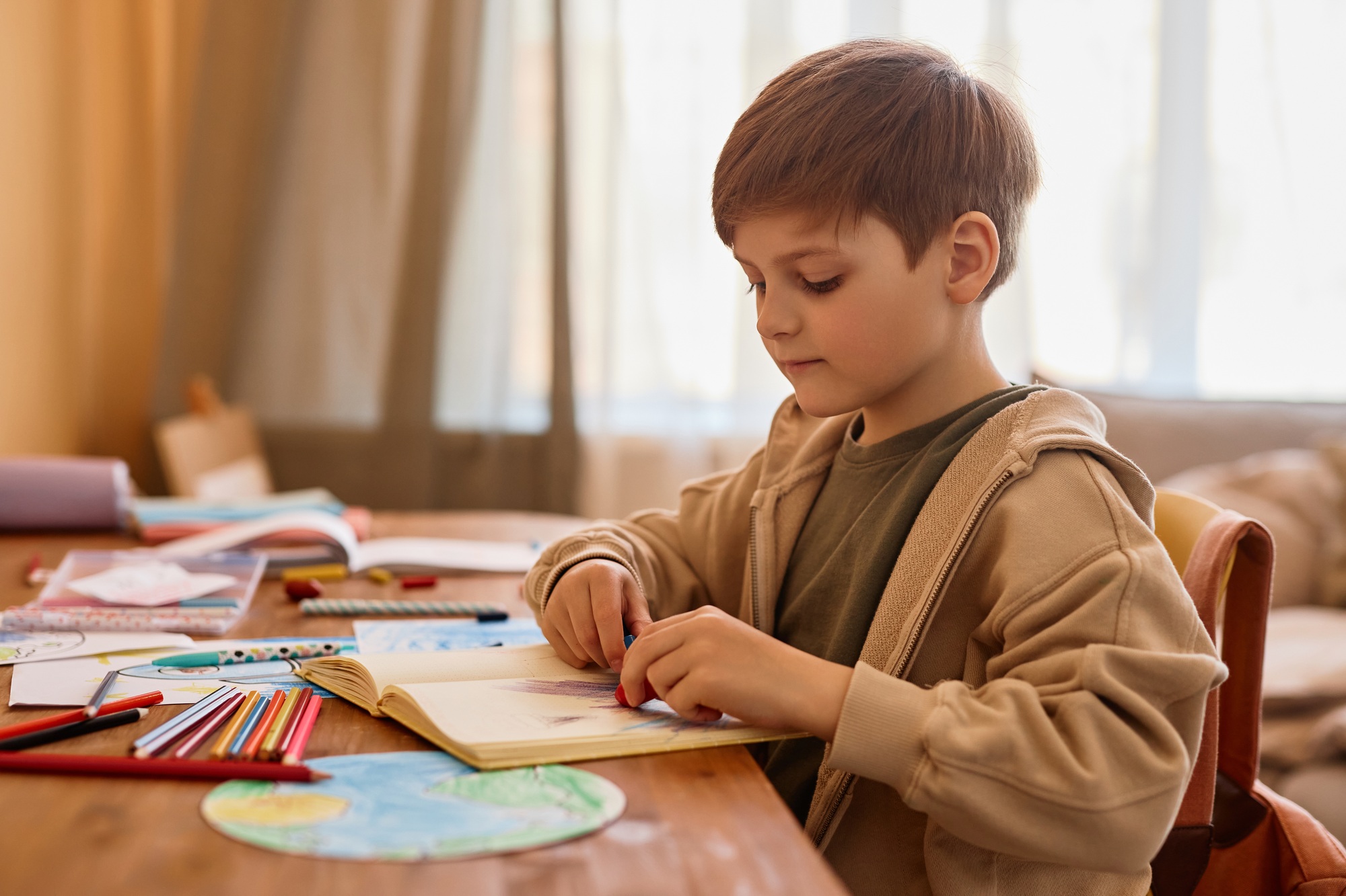 Cute boy drawing at table