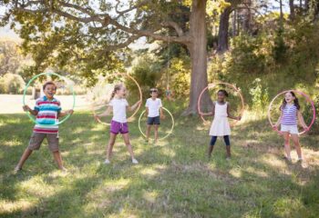 Group of cheerful friends playing with hula hoops at campsite