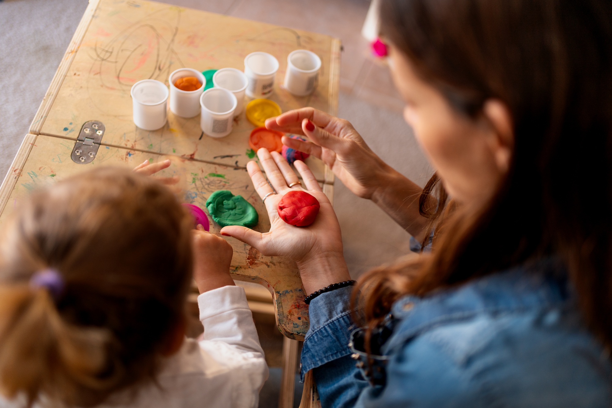 Mother and daughter playing with modeling clay at home