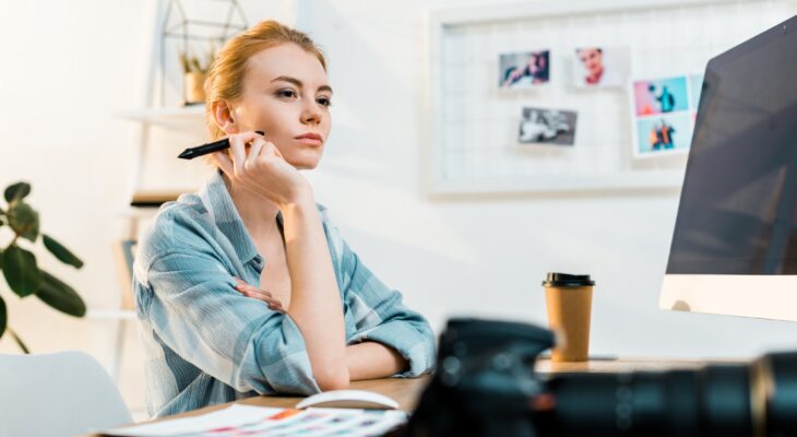pensive young retoucher using desktop computer and drawing tablet in office