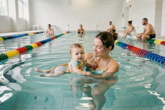 Mère et bébé nageur dans une piscine couverte moderne des Bouches-du-Rhône, flottant ensemble dans une eau turquoise claire